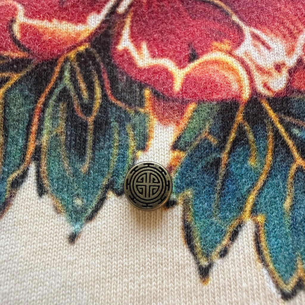 Round metal detail against red floral artwork on the Babo Horangi Tee